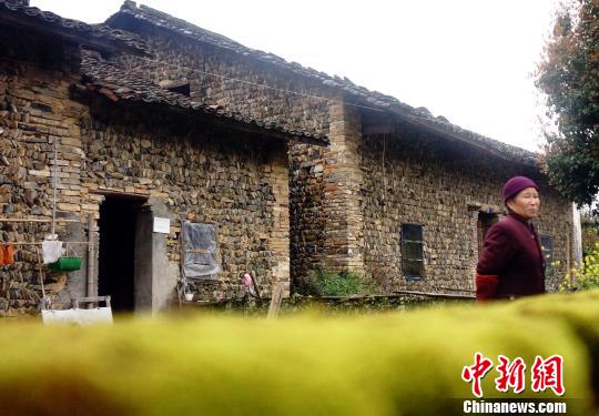 一位老人走出其居住的石头屋。石头屋多建在河畔,取材自河中或山间石块,以石为墙,以木为梁,冬暖夏凉。3月29日拍摄。 王昊阳 摄